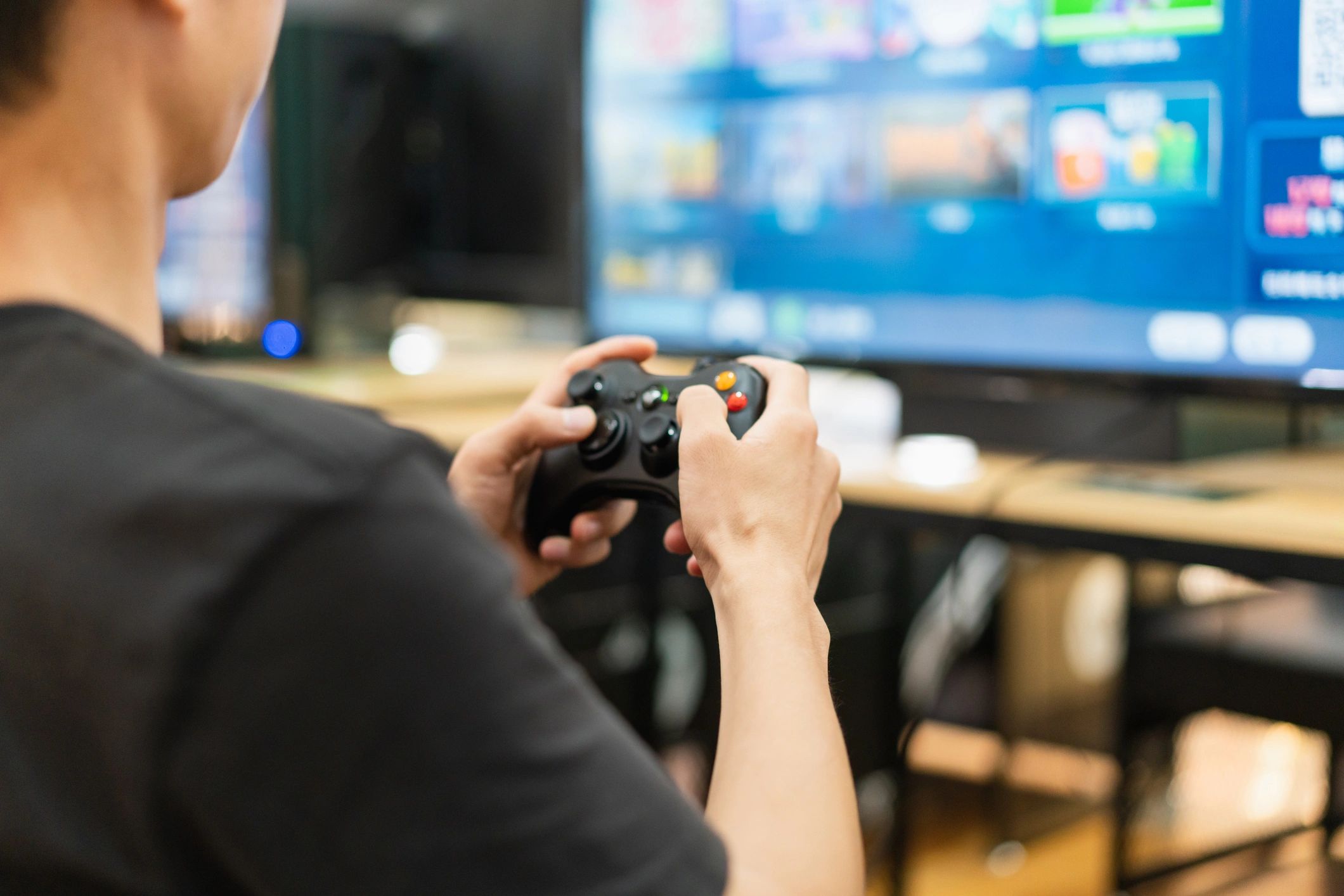 Person holding a gaming controller playing a video game on TV.