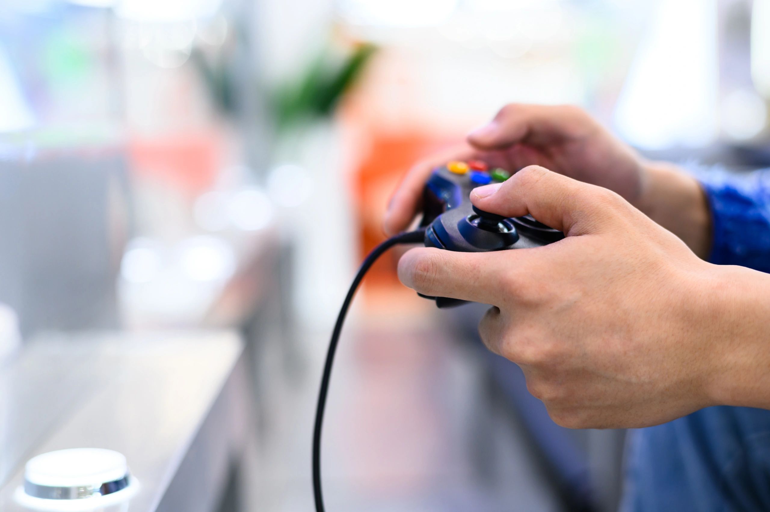 Person holding a wired video game controller, ready to play.