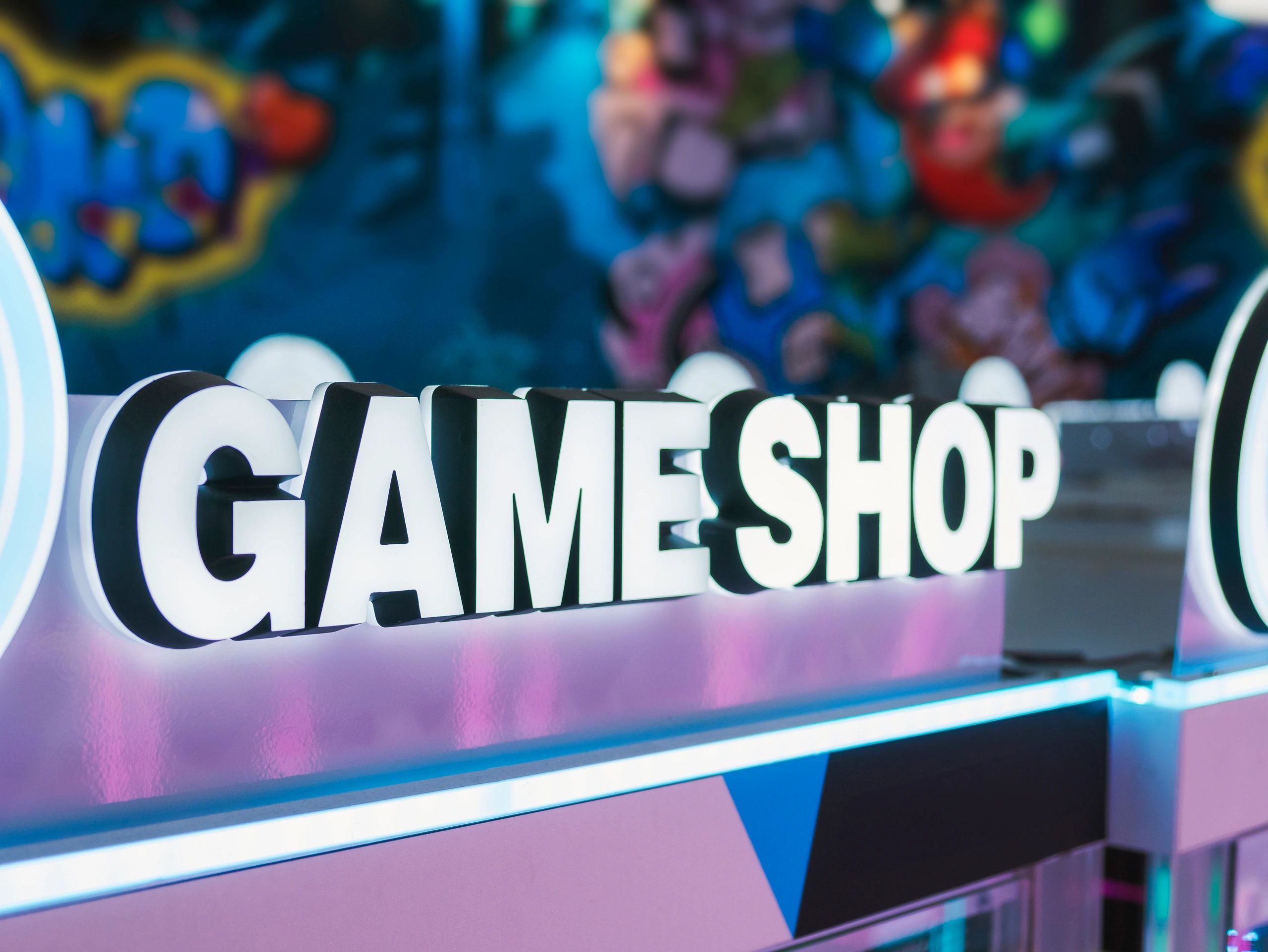 Illuminated sign reading 'GAME SHOP' in a vibrant store setting.