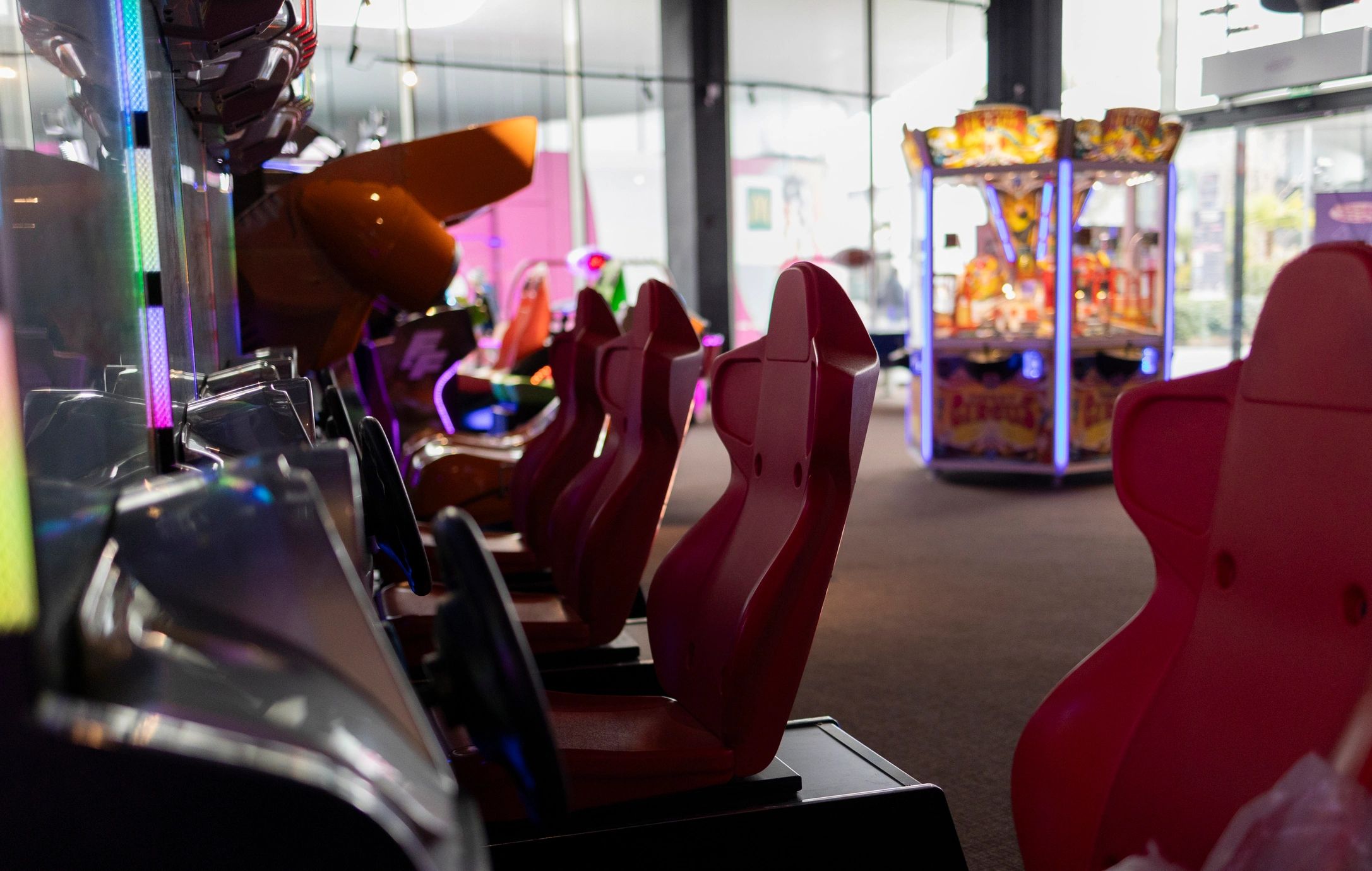 Red gaming chairs in an arcade with bright machines.